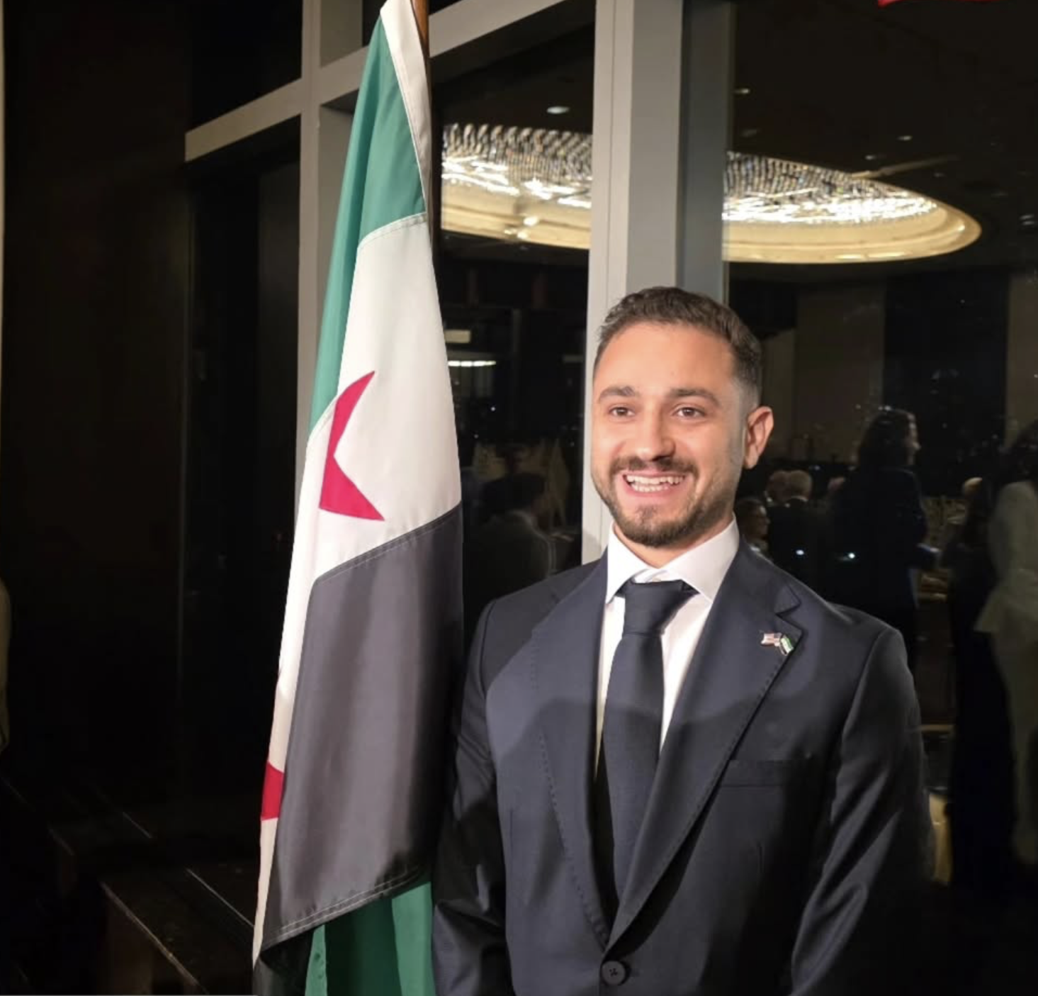 Joe Jajati beside Syrian flag